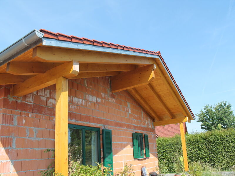 Vordach aus Holz mit sichtbarer Balkenkonstruktion