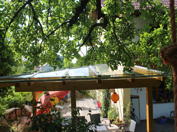 Glasüberdachte Holzpergola unter Bäumen