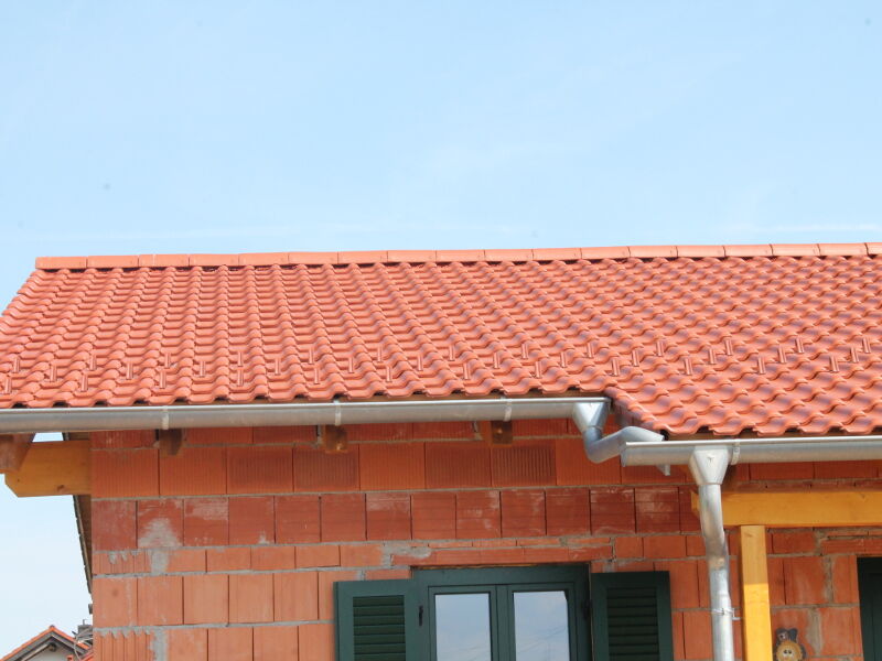 Fertig gedecktes rotes Ziegeldach mit Dachrinne