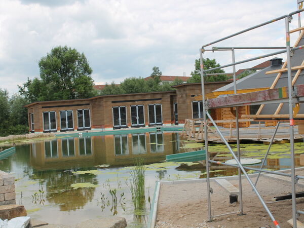 Gebäude mit Holzfassade an einem Naturteich