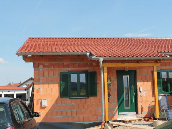 Rohbau mit neuem roten Ziegeldach und Holzvordach